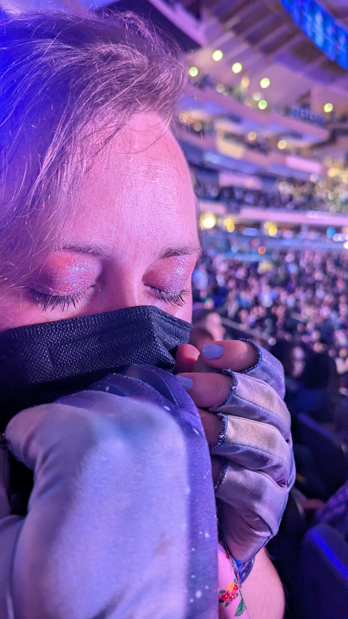 close up of PJ's face, her eyes are closed and have sparkly purple shadow on them. she's got her hands in purple gloves, held up to her mouth, which is covered in a black mask. 