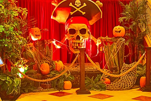 a orange-filtered display of plants, pumpkins, and a large skull and cross bones with a pirate hat on